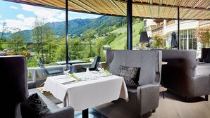 A dining area with a table set for two, overlooking a scenic mountain view.