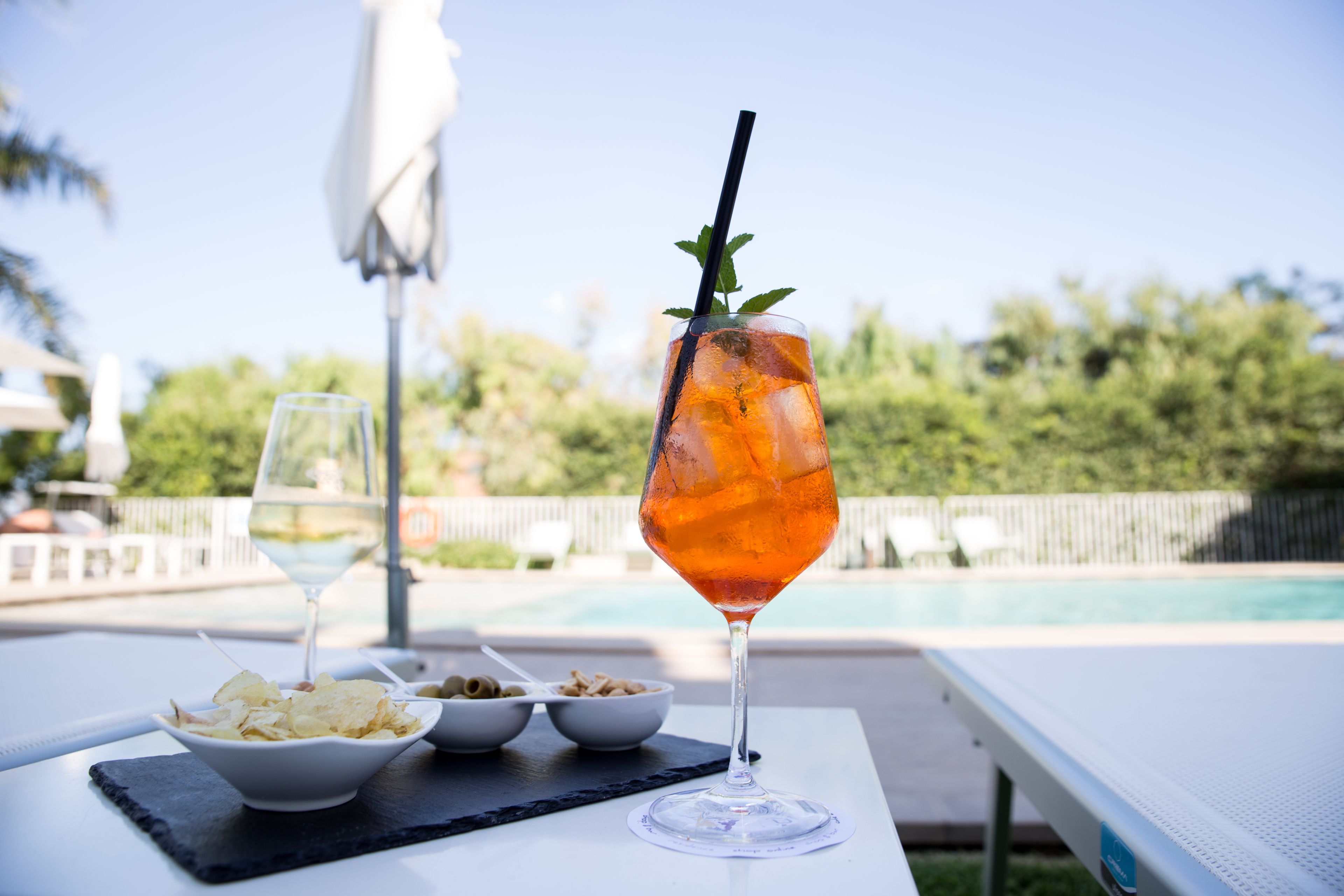 Une table avec un verre de boisson à l’orange, un bol de chips et un bol de céréales.