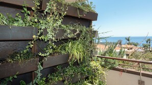 Un balcón con jardineras verticales llenas de plantas diversas y vista al océano.