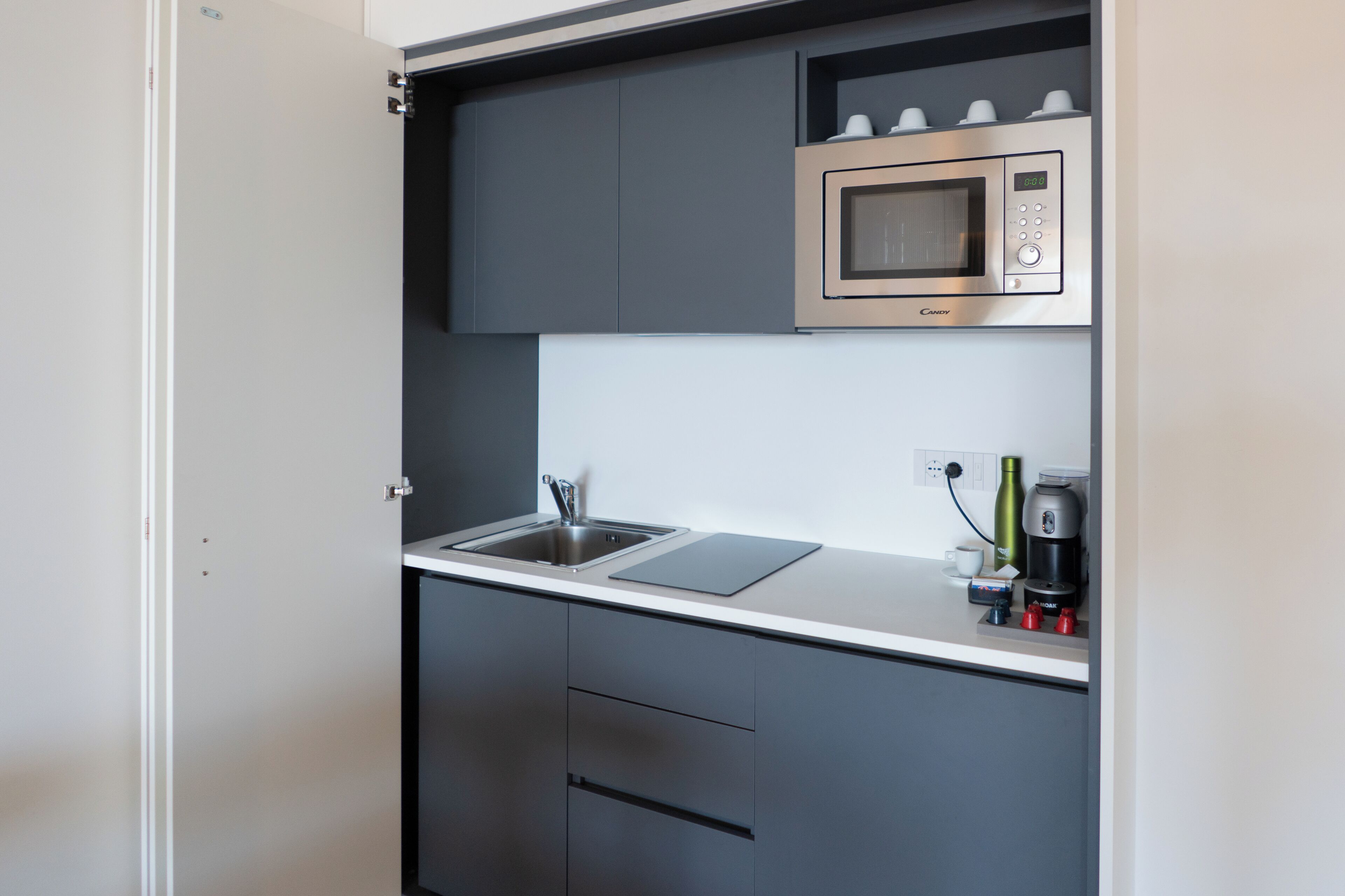 Una cocina compacta equipada con microondas, pileta y cafetera.