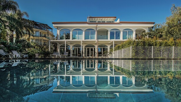 Una casa grande de dos pisos con una piscina delantera.
