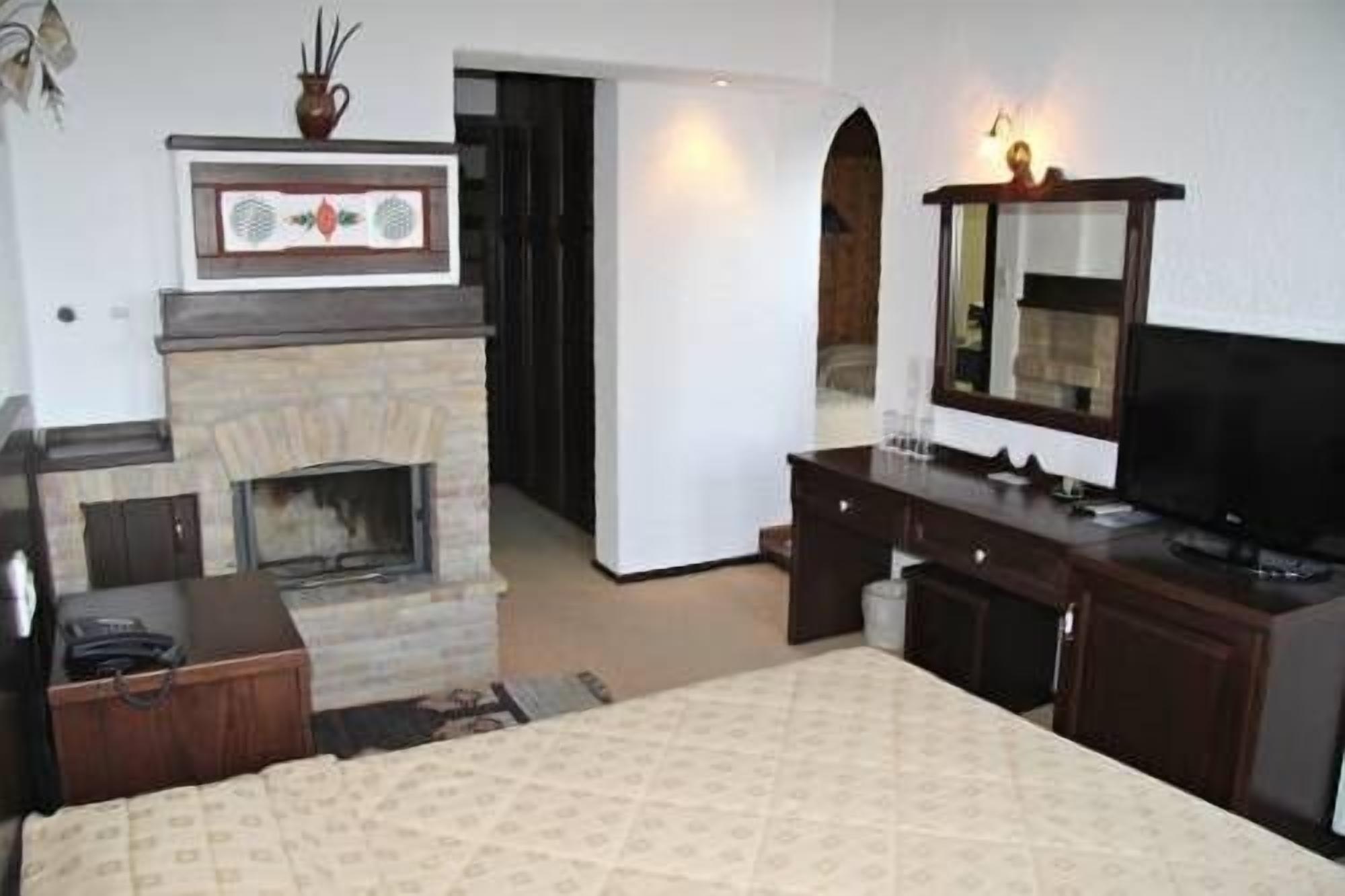 Una habitación de hotel con chimenea, televisor, escritorio y cama.