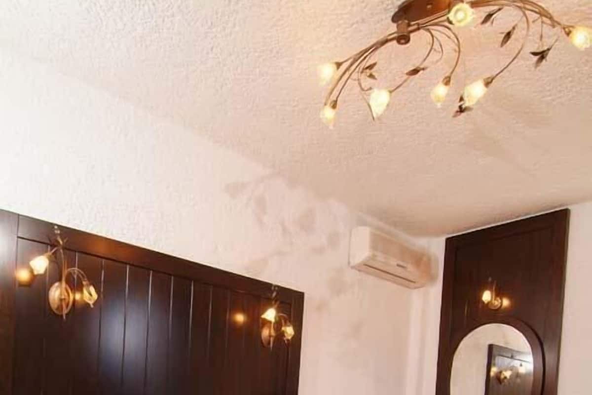 Une chambre à coucher avec un grand lit, une tête de lit en bois foncé, un miroir et un luminaire fixé au plafond.