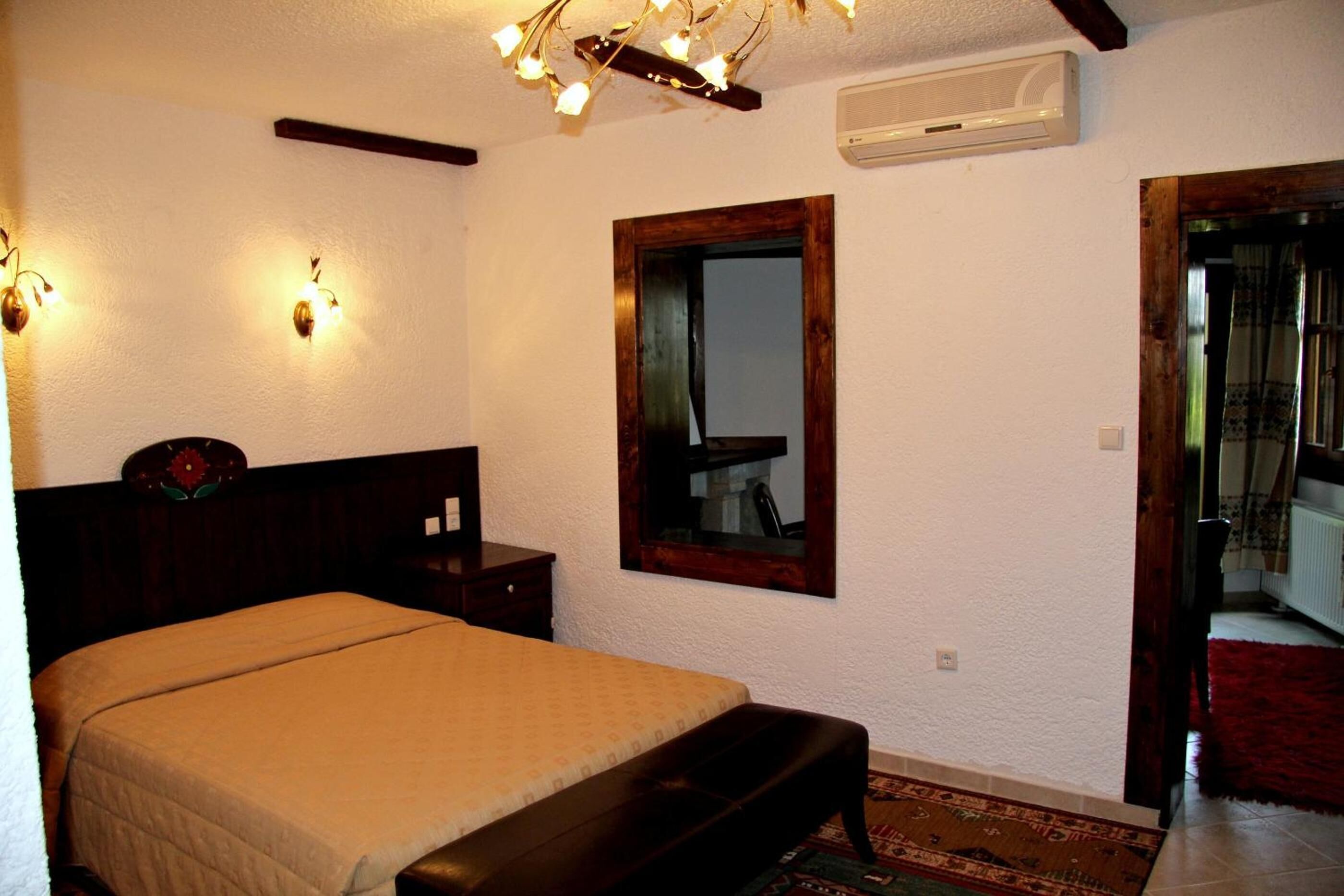Une chambre à coucher comprenant un lit, des tables de chevet, un miroir et un luminaire au plafond.