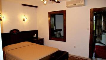Une chambre à coucher comprenant un lit, des tables de chevet, un miroir et un luminaire au plafond.