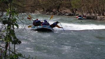 A group of people in a raft navigating a river surrounded by trees.