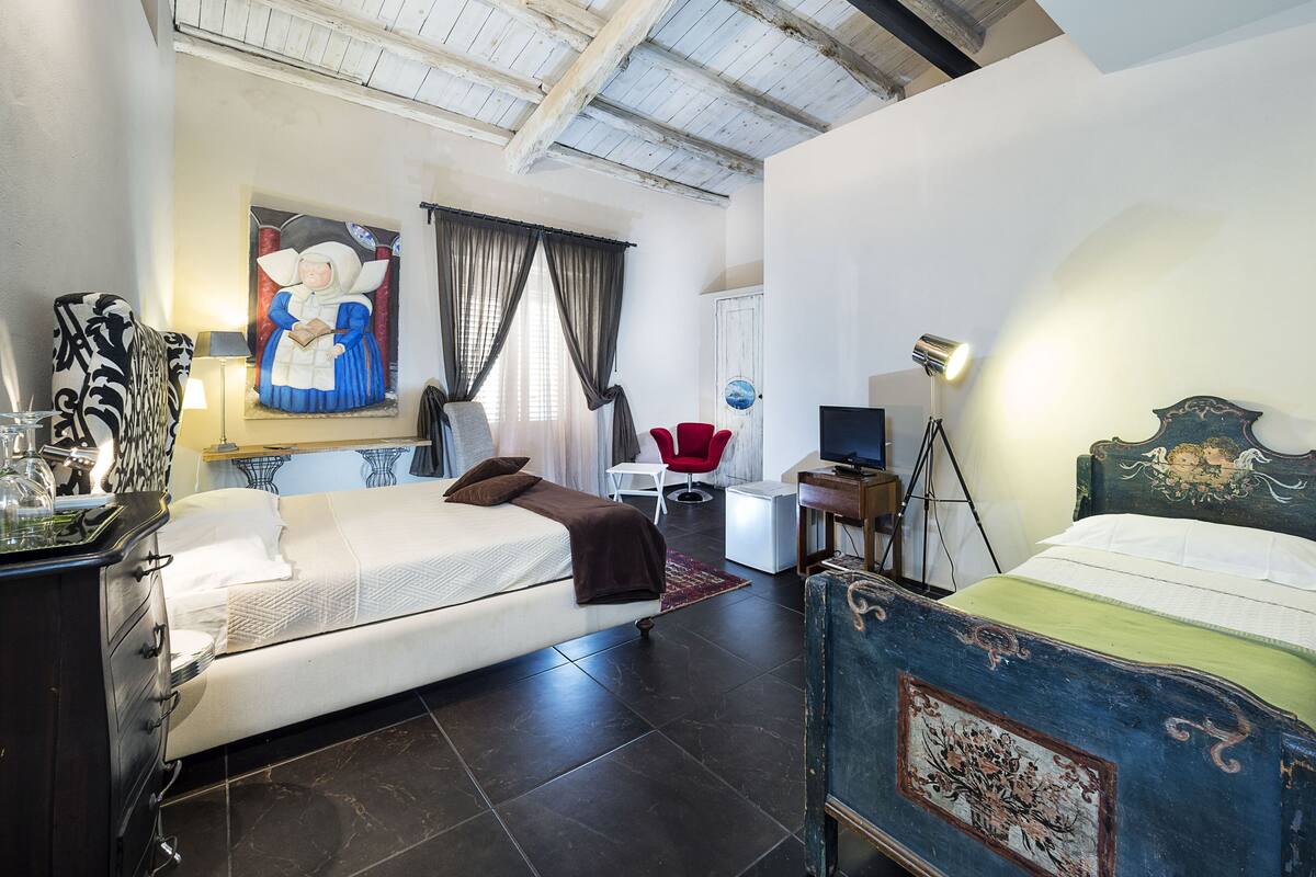 Une chambre d’hôtel avec deux lits, un bureau, une chaise, une télévision et un tableau au mur.