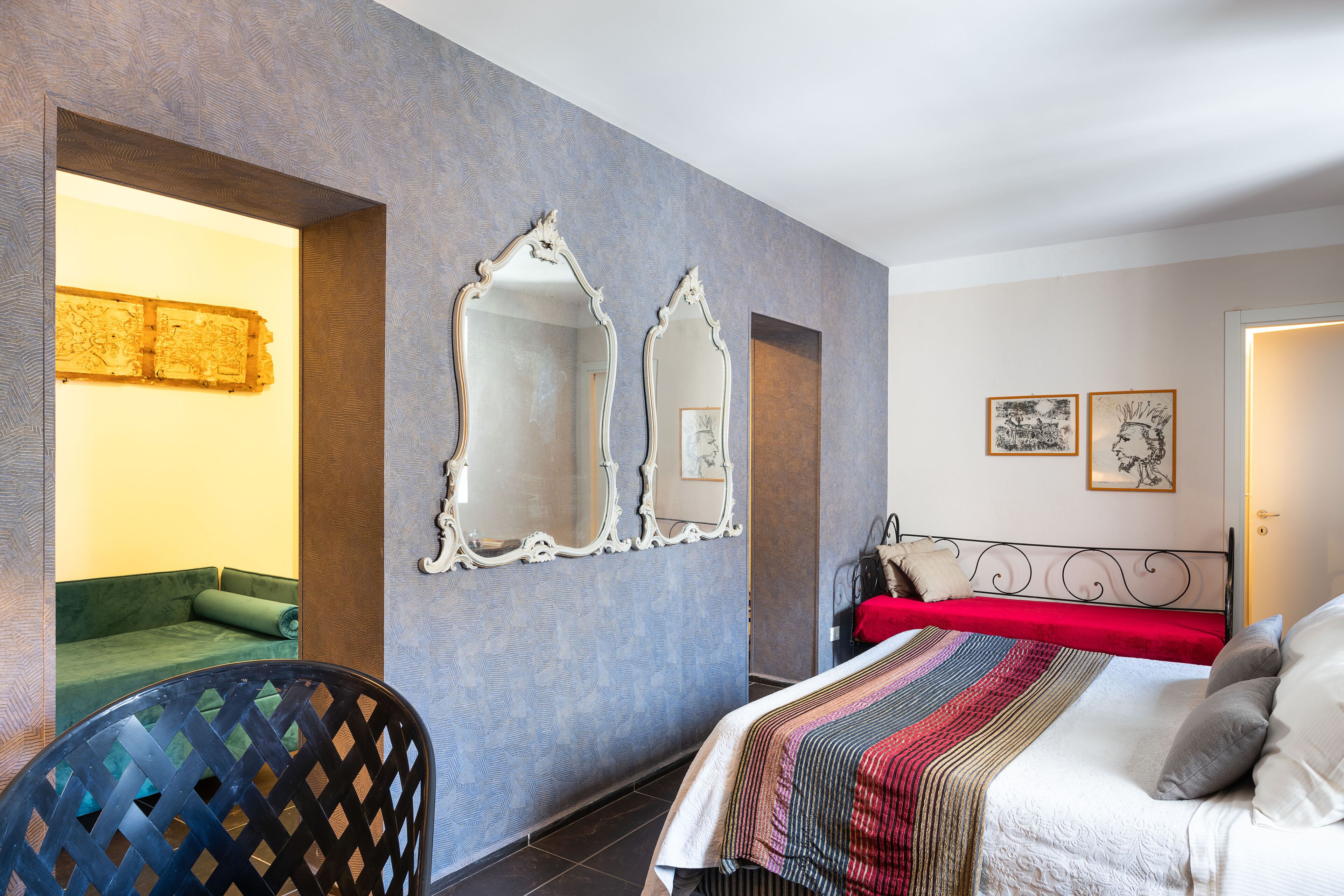 Habitación de hotel con una cama, una silla y un espejo grande en la pared.