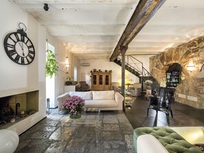 Ein geräumiges Wohnzimmer mit Kamin, Treppe und einer rustikalen Steinwand.