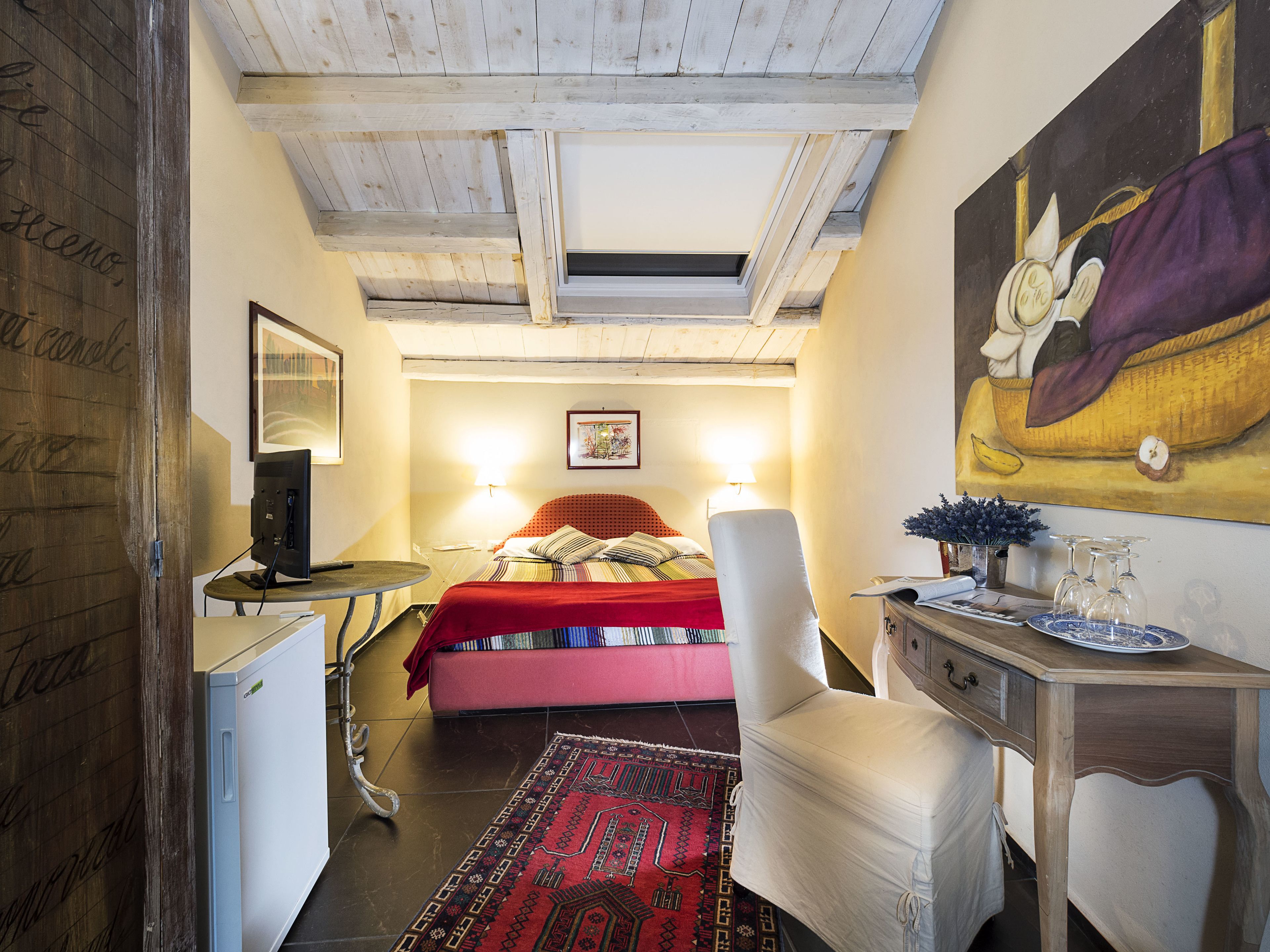 Ein gemütliches Schlafzimmer mit einem Bett, Nachttischlampen, einem Schreibtisch und einem Bild an der Wand.