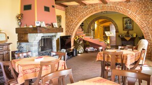 A cozy restaurant with brick arches, wooden tables, and a fireplace. - Cascina Bellavista (Tigliole)