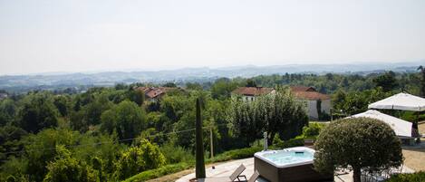A hot tub in a landscaped outdoor area with lounge chairs and a view of a hilly landscape.