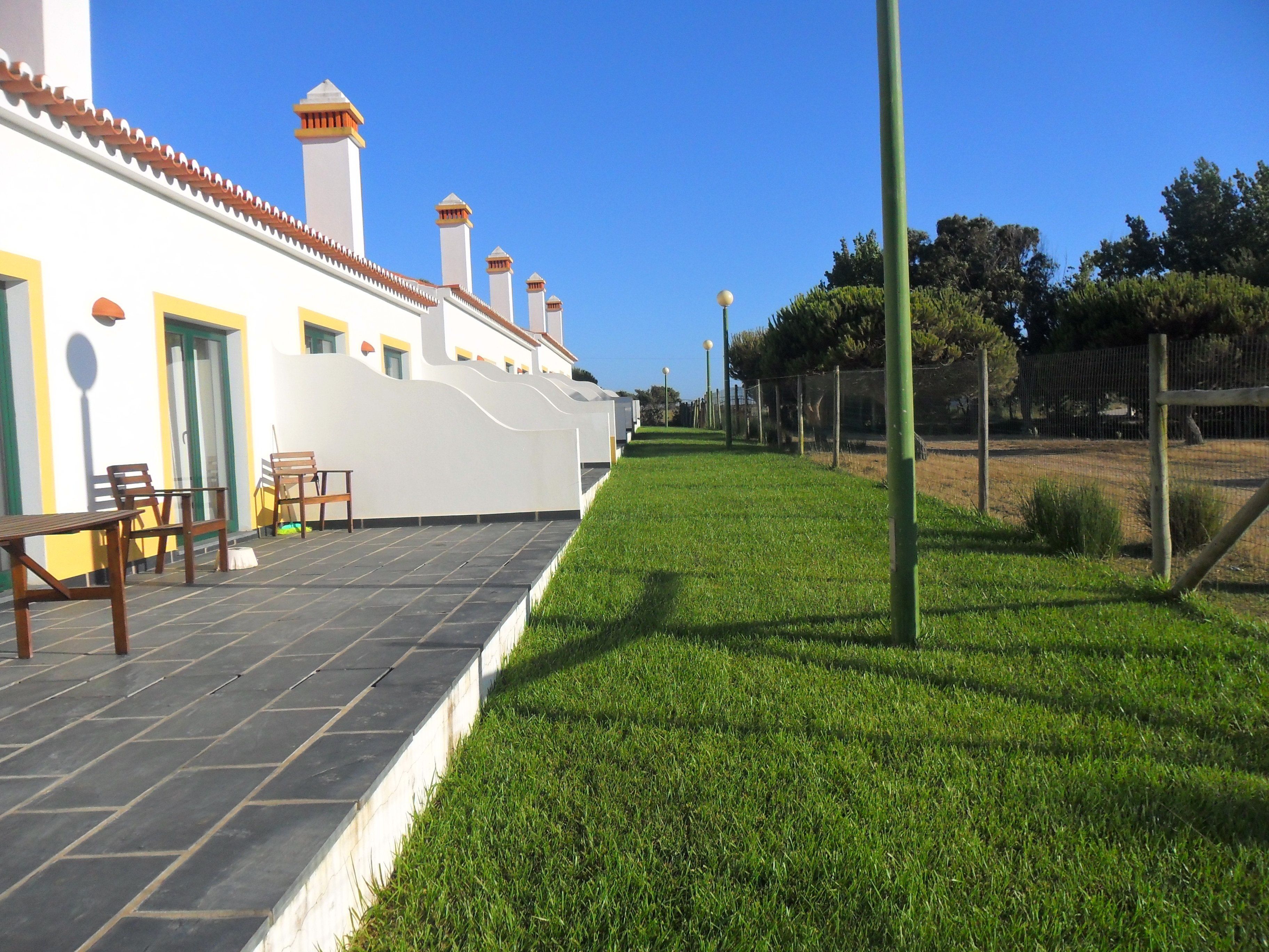 A building with a white exterior, multiple chimneys, and a paved patio area with outdoor furniture.
