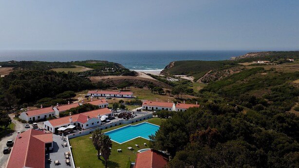 Un resort con varias edificaciones, una piscina y vista al océano.