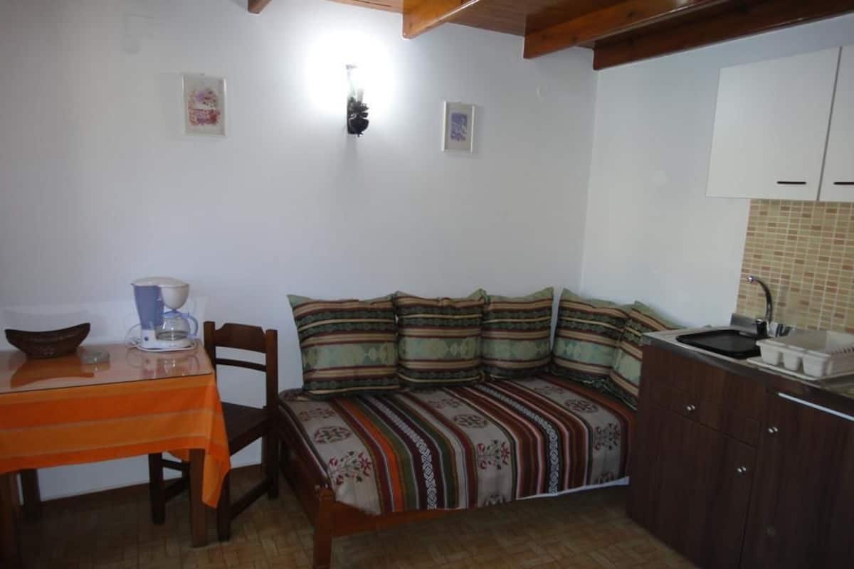 Uma cozinha compacta com mesa e cadeiras, um banco com almofada estampada e painel de azulejos.