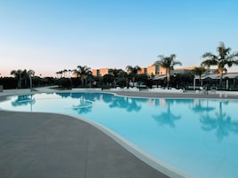 Una piscina al aire libre de temporada, sombrillas, tumbonas