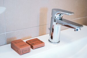 Un baño con un grifo cromado y dos pastillas de jabón sobre el mostrador.