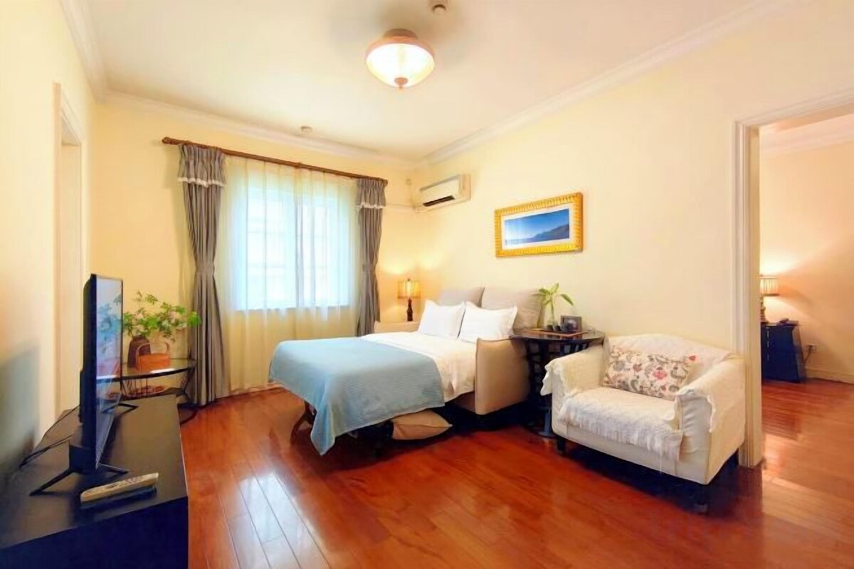 A hotel room with a bed, a sofa, a desk with a computer, and a television.