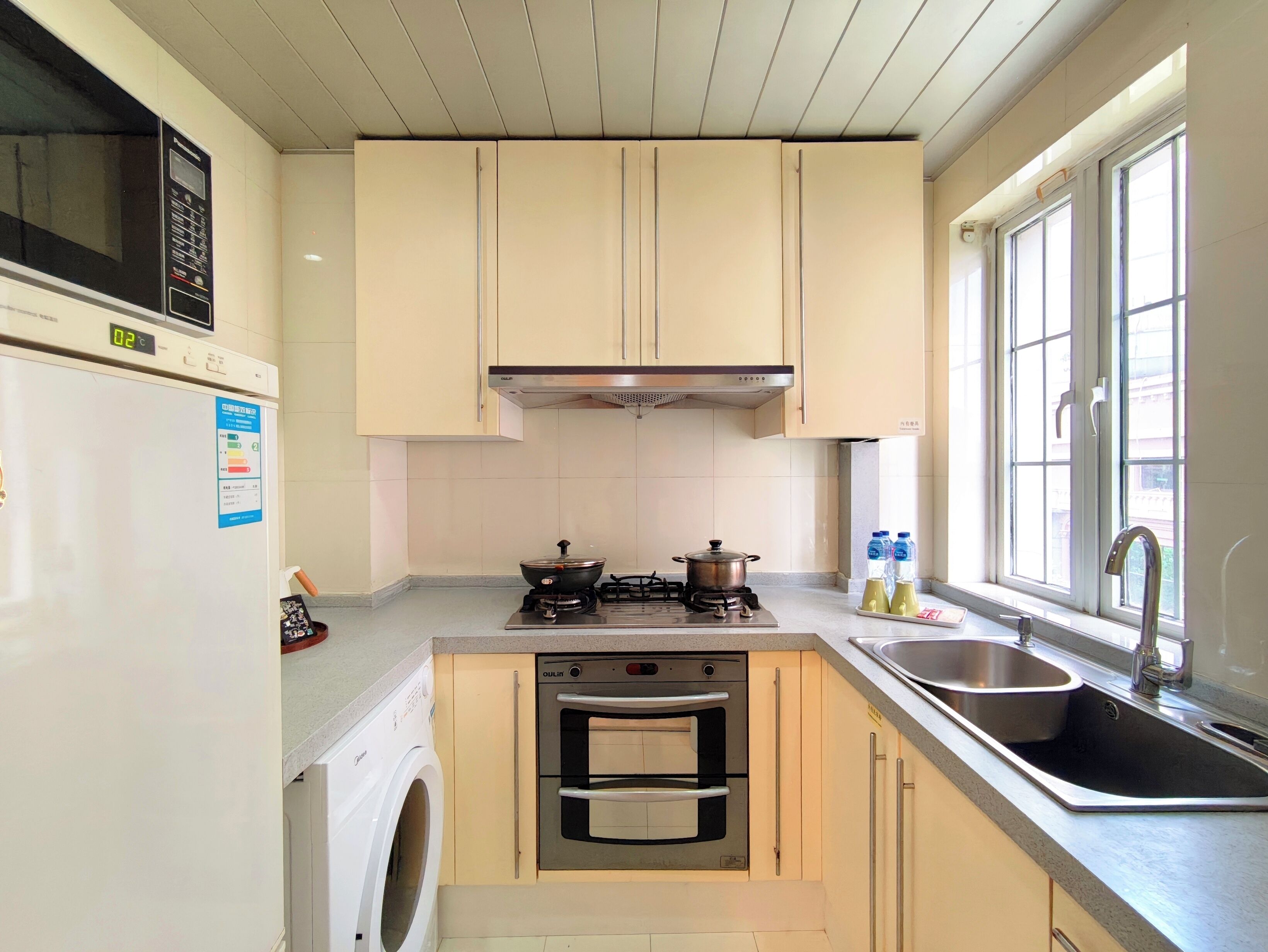 A kitchen with a microwave, stove, oven, sink, and washing machine.