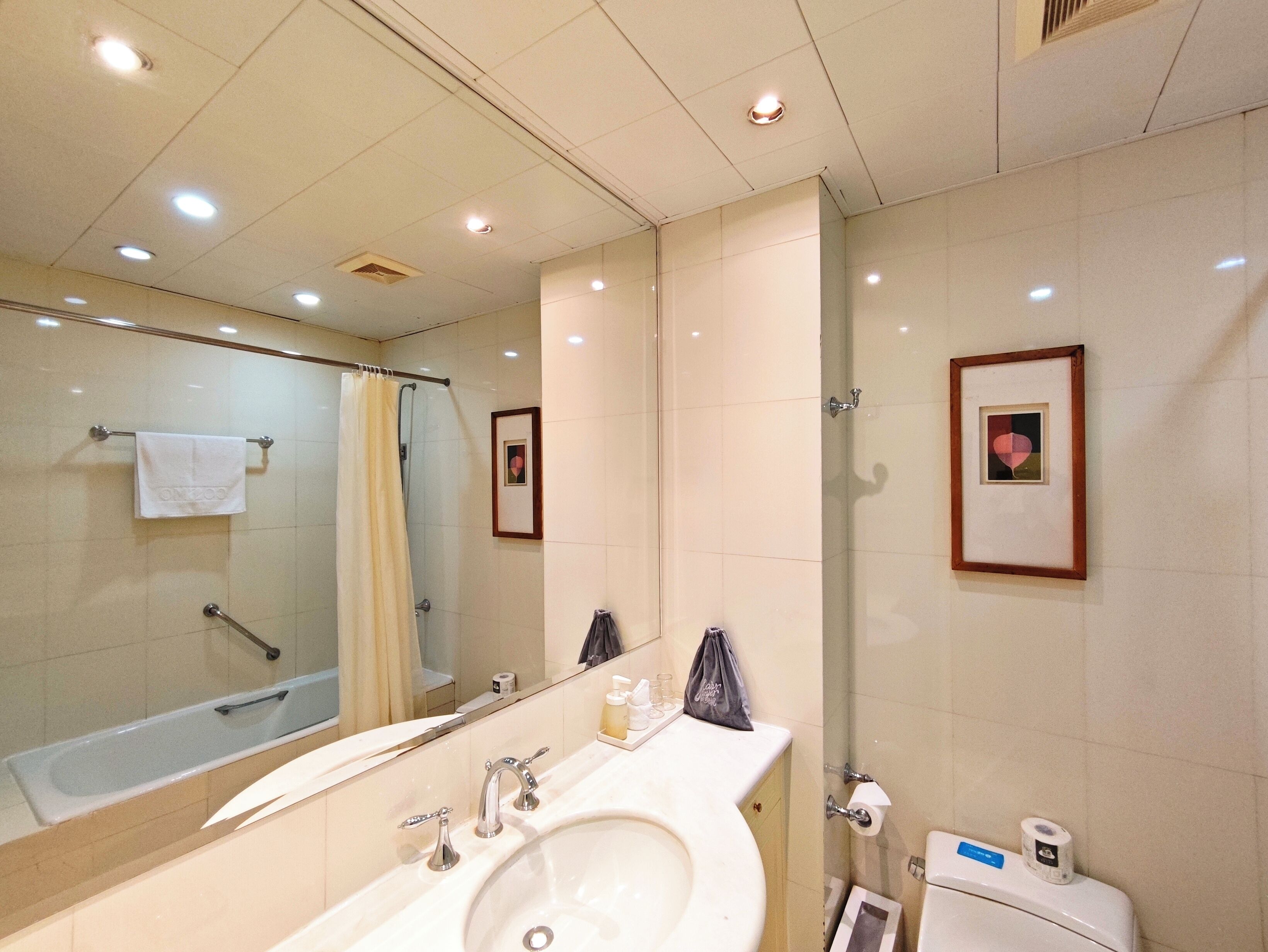 Un baño moderno con un espejo grande, una bañera, un lavamanos y un inodoro.