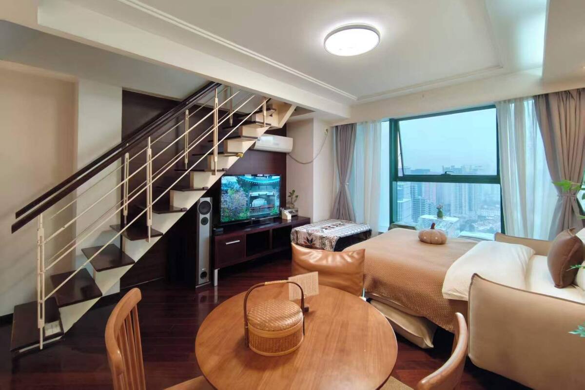 Uma sala de estar moderna com escada, televisão, sofá, mesa de jantar e vista para a cidade.