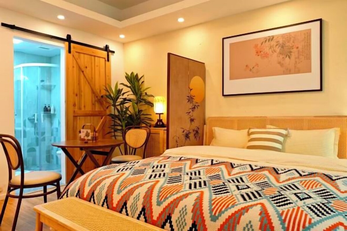 A hotel room with a bed, a desk, a chair, and a door leading to a bathroom.