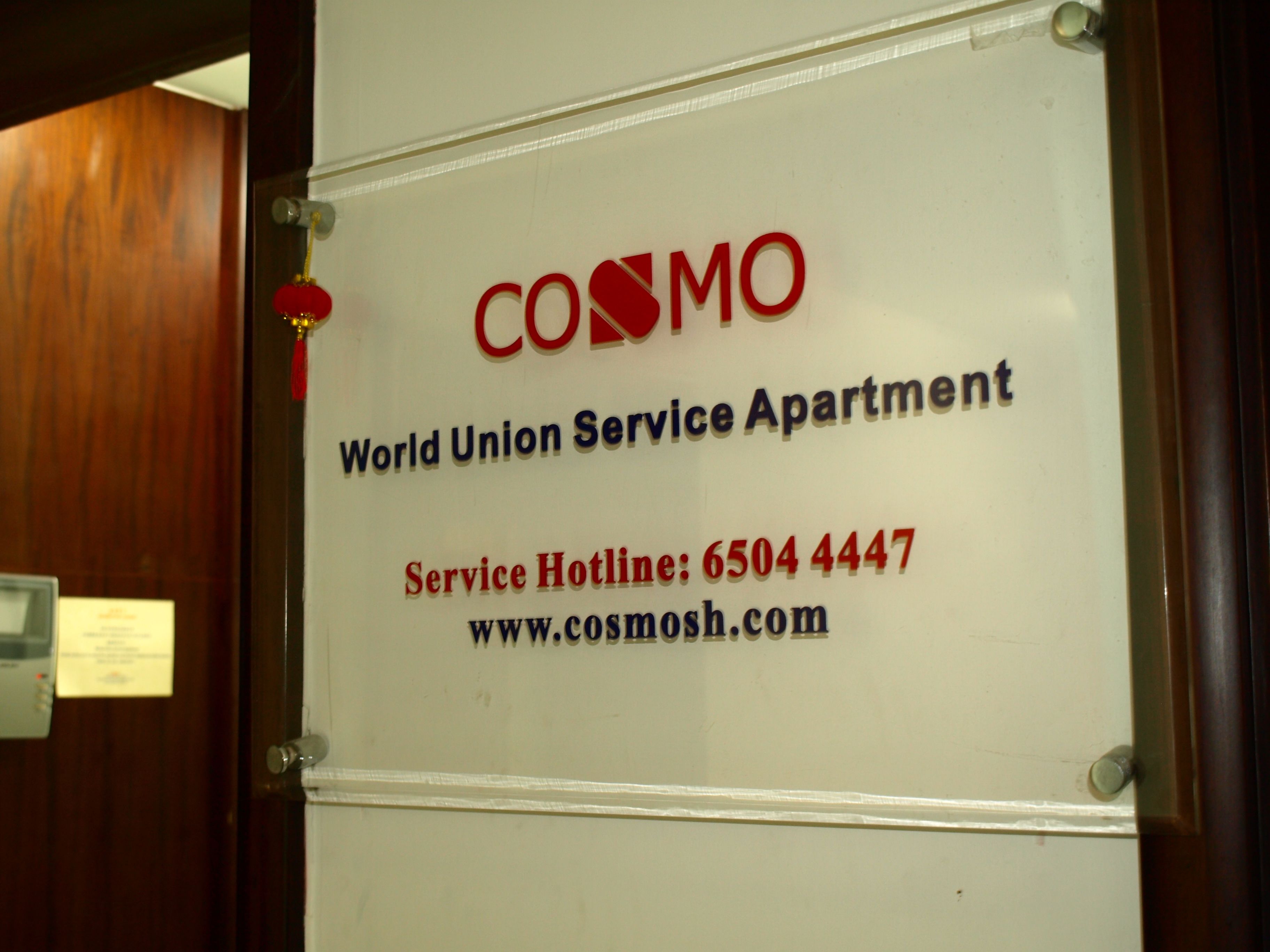 Eine Tür mit einem Schild für 'COSMOS World Union Service Apartment' und einer Service-Hotline-Nummer.