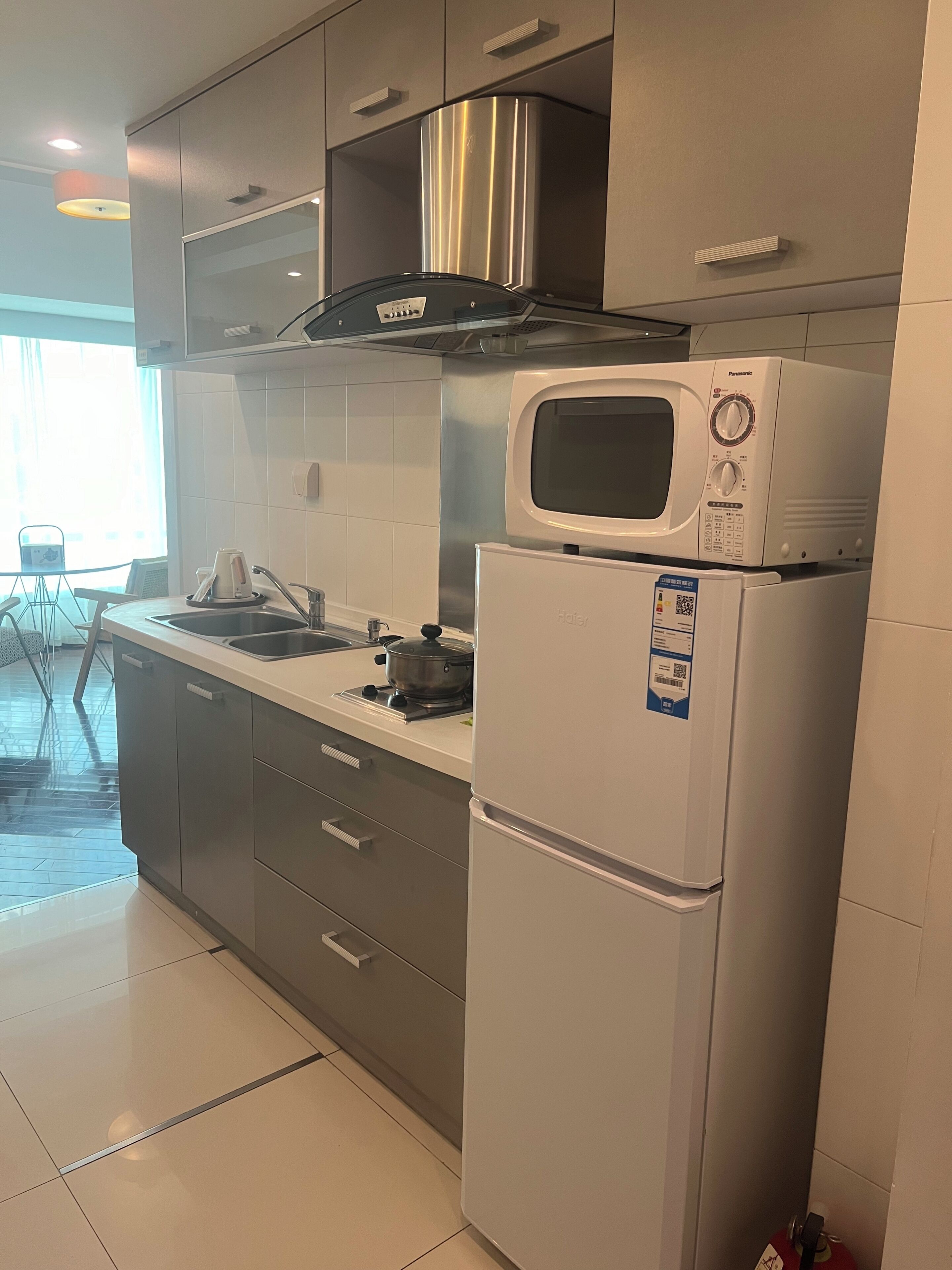 Une cuisine moderne équipée d’une hotte en acier inoxydable, d’un four à micro-ondes et d’un réfrigérateur.
