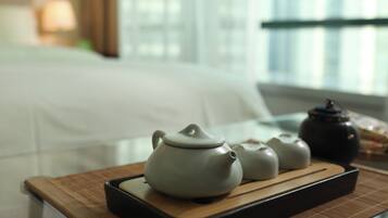 A tea set on a tray with a bed in the background.