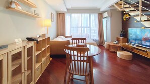 Habitación de hotel con cama, escritorio con lámpara, televisor, escalera y ventana con cortinas.