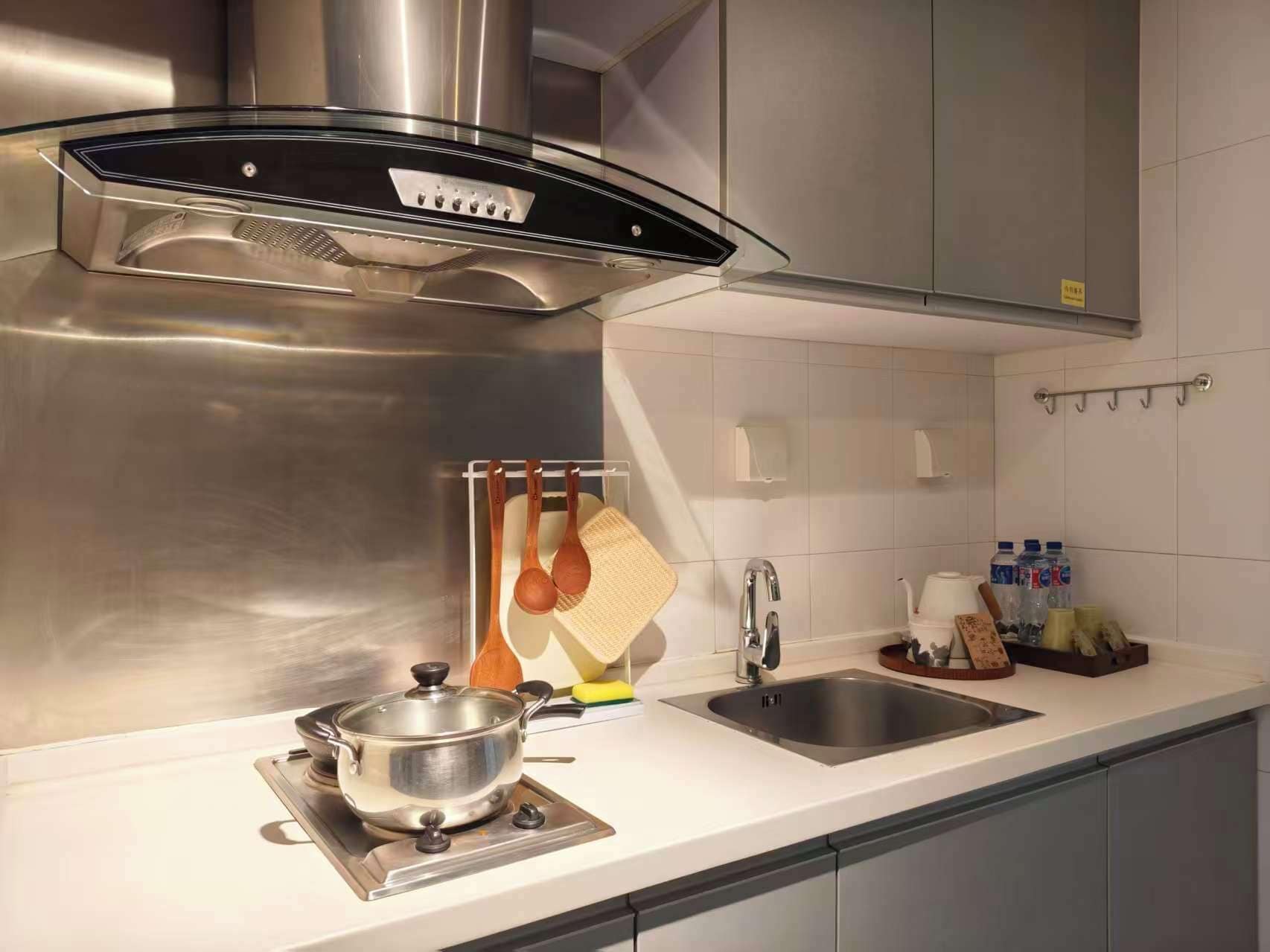 A modern kitchen with stainless steel appliances, a sink, and a countertop with utensils.