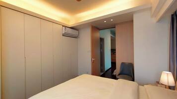 Une chambre d’hôtel équipée d’un lit, d’un bureau, d’une chaise, d’un climatiseur et d’une lampe.