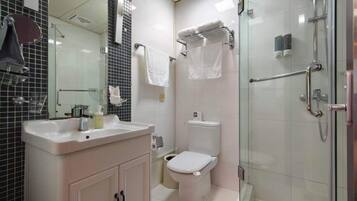 A modern bathroom with a glass-enclosed shower, a white sink with a mirror, and a toilet.