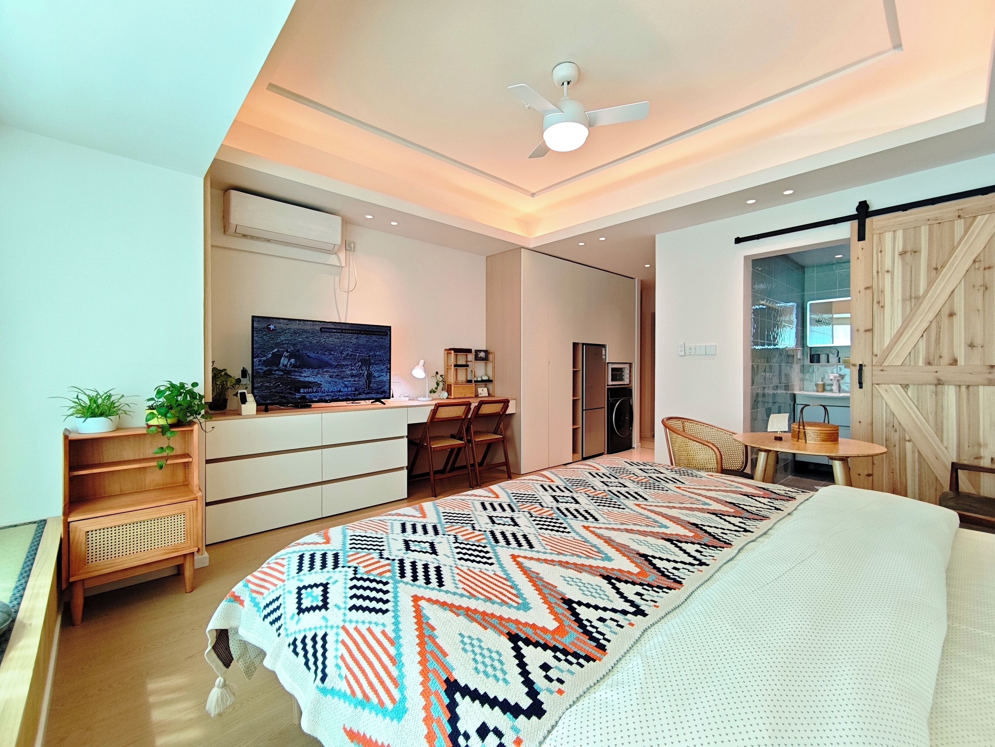 Un dormitorio moderno con cama, escritorio, televisor y armario.