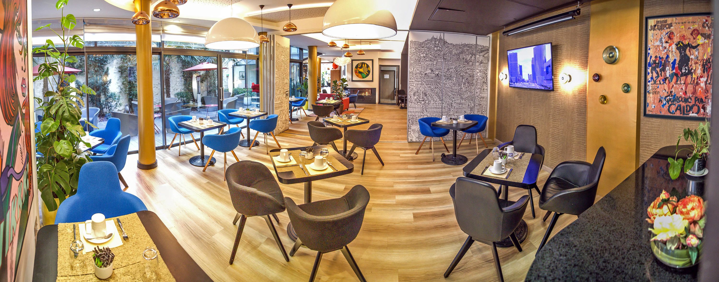 Un restaurant moderne avec des chaises bleues et noires, des tables en bois et une fresque murale représentant un paysage urbain.