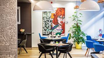 A modern dining area with black chairs, round tables, and a large potted plant.