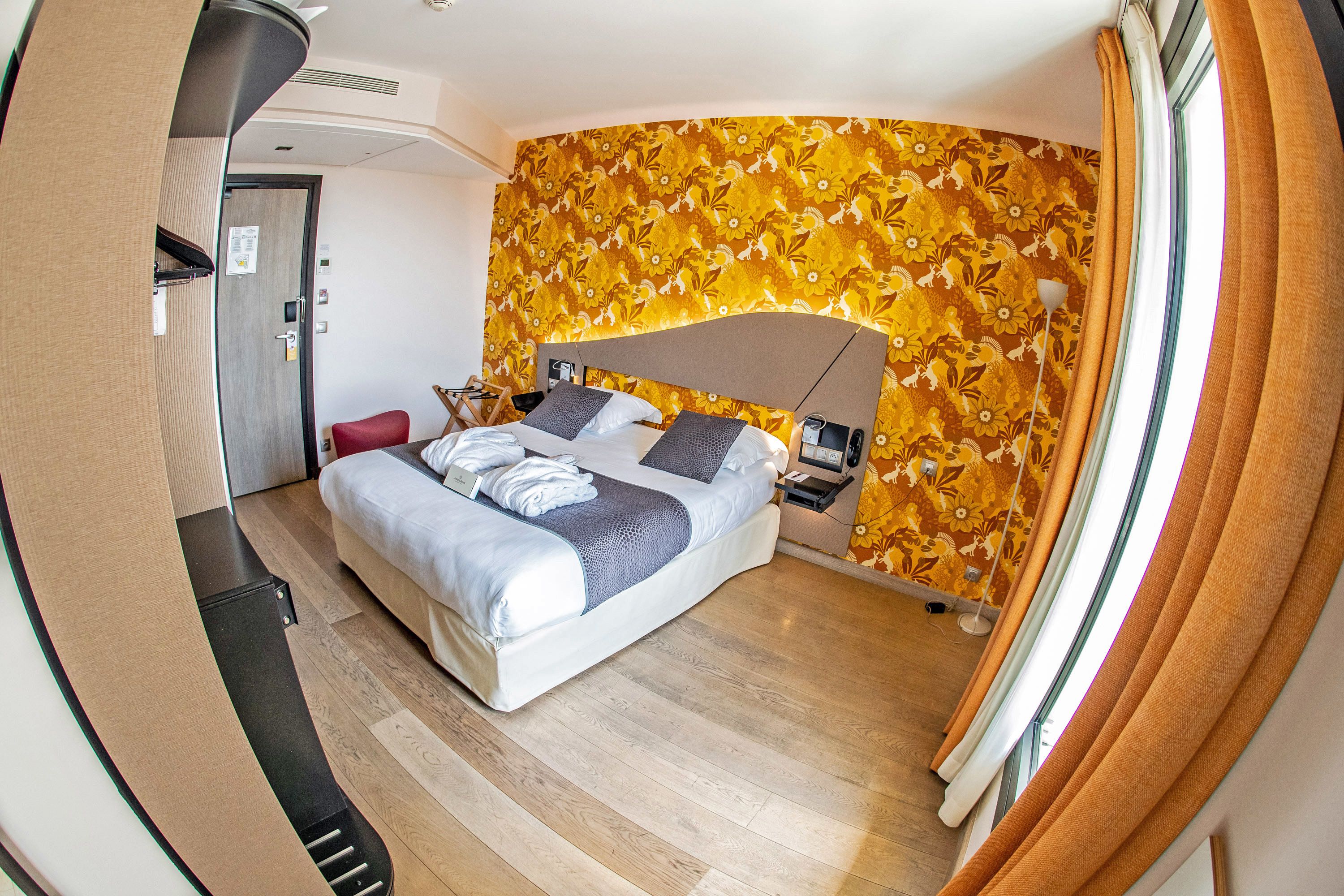 Ein modernes Hotelzimmer mit Bett, Schreibtisch und einer Duschkabine.