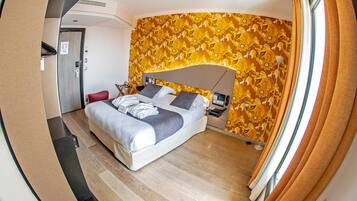 Ein modernes Hotelzimmer mit Bett, Schreibtisch und einer Duschkabine.