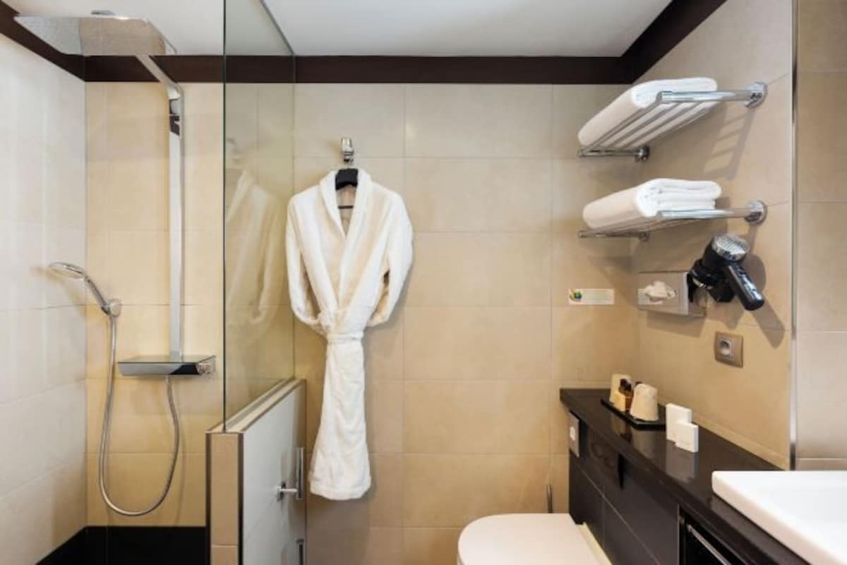 Un baño moderno con cabina de ducha de vidrio, bañera blanca y tocador con espejo y toallero.