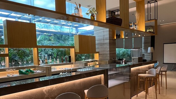 A modern bar area with a glass enclosure, bar stools, and a view of greenery outside. - Holiday Inn Express Manila Newport City by IHG (Pasay)