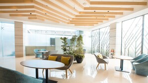 A modern interior with a wooden ceiling, glass walls, and a central plant. - Holiday Inn Express Manila Newport City by IHG (Pasay)