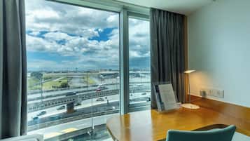 A hotel room with a large window offering a view of a highway and cityscape.