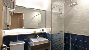 A modern bathroom with a glass shower enclosure, a white toilet, and a sink with a mirror above it.