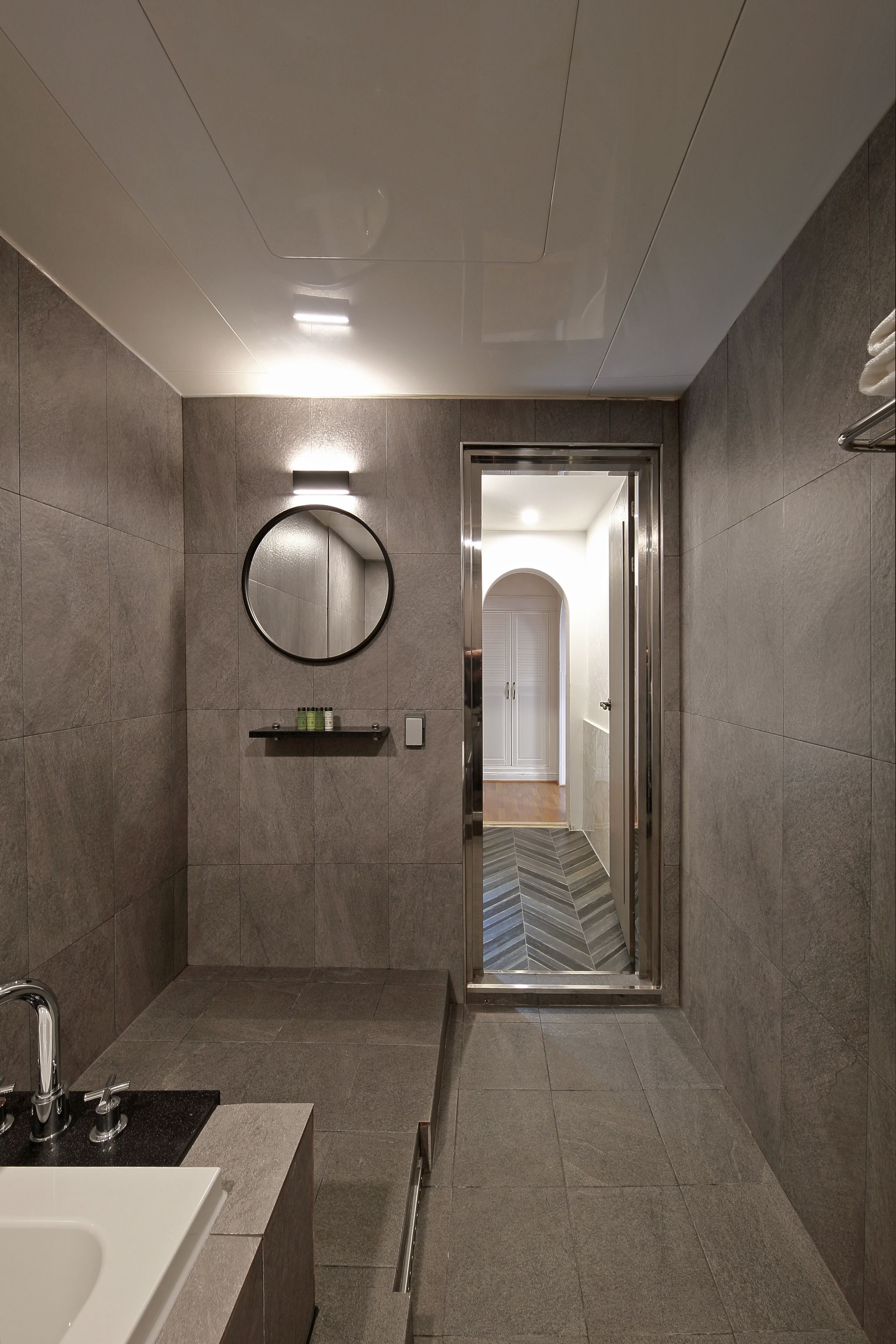 A modern bathroom with a large mirror, a built-in sink, and a shower area.