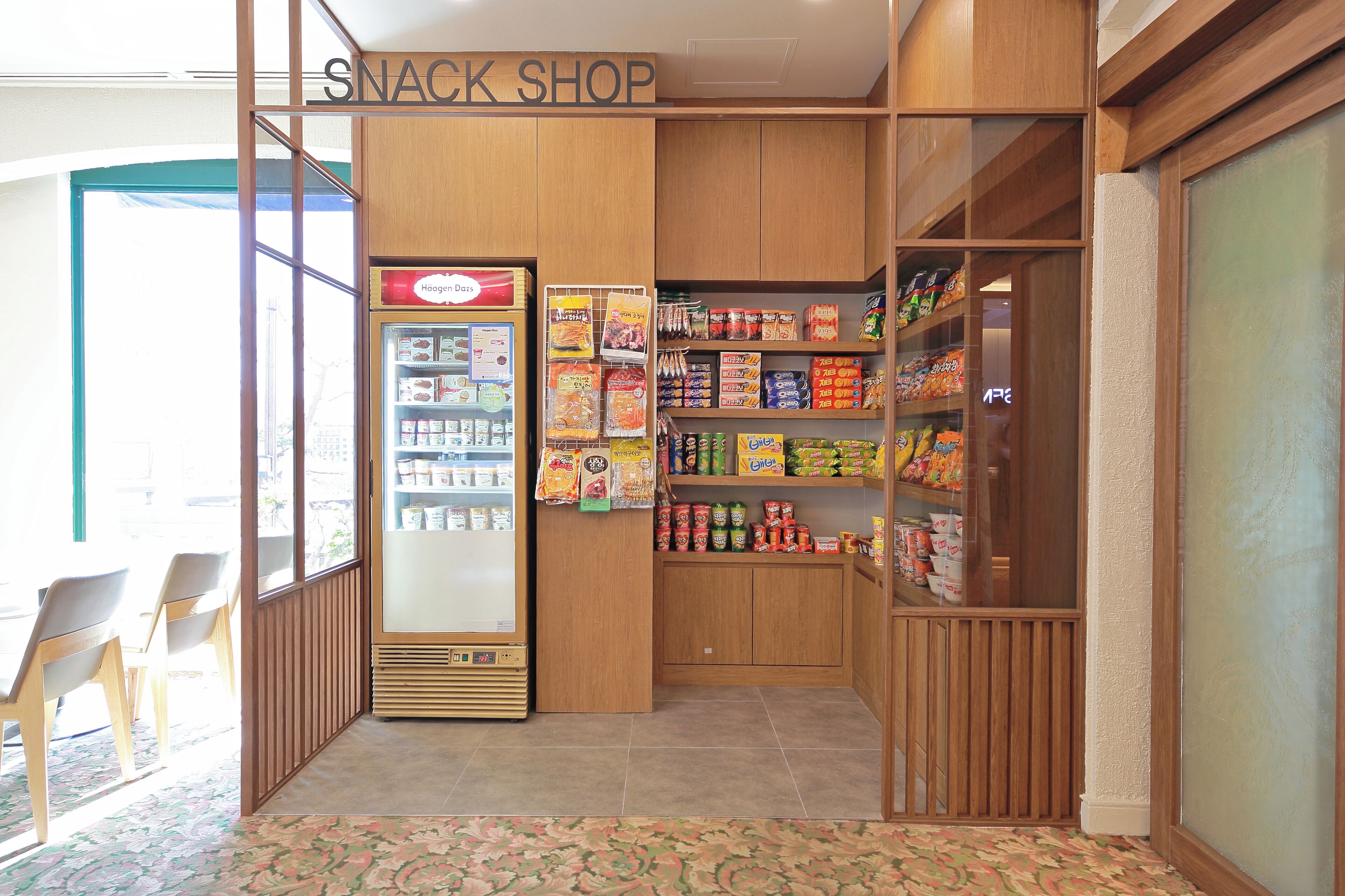 A snack shop with a refrigerated display and shelves stocked with snacks.