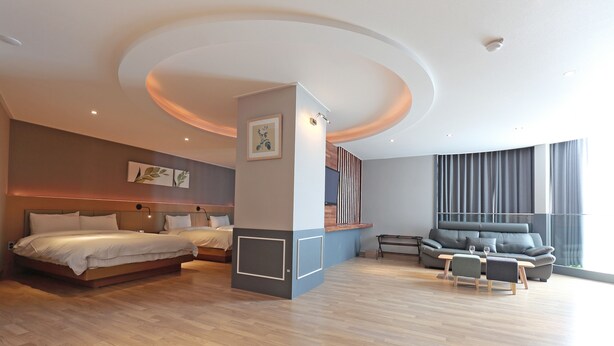 Une chambre d’hôtel moderne dotée d’un grand lit, d’un canapé, d’un coin repas et d’une grande fenêtre.