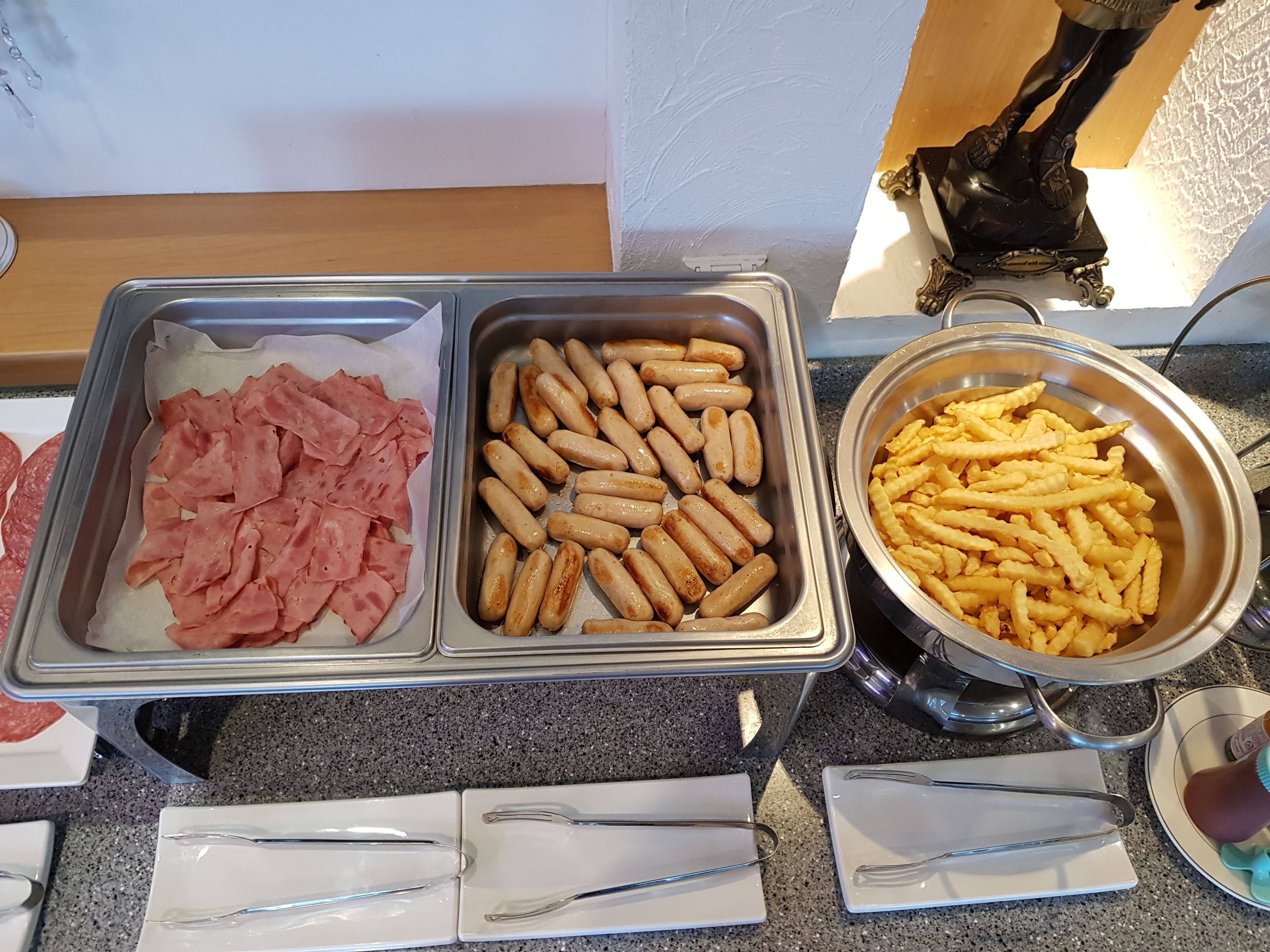 Un buffet proposant des plateaux de viandes tranchées, de saucisses et de frites.