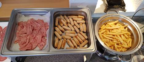 Un buffet proposant des plateaux de viandes tranchées, de saucisses et de frites.