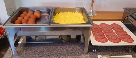 Montaje de bufé con huevos, huevos revueltos y salami en rodajas.