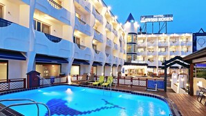 Un hôtel doté d’une piscine, d’un espace extérieur aménagé et d’une enseigne indiquant « Hôtel Swiss Rosen ».